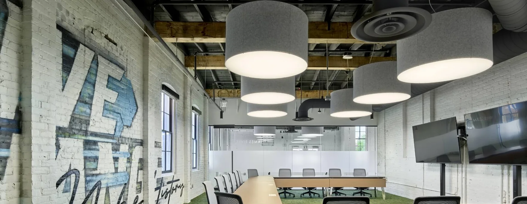 Commercial interior lit by suspended drum pendants over a meeting table