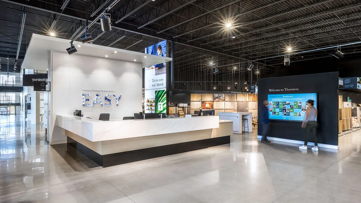 Flooring showroom with track lighting across an exposed black ceiling and illuminated sample displays
