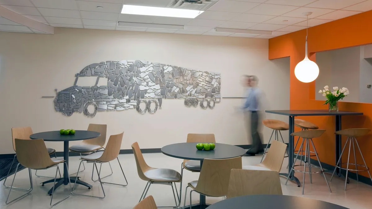 Office break area with pendant lighting over tables and a wall-length illustrated graphic
