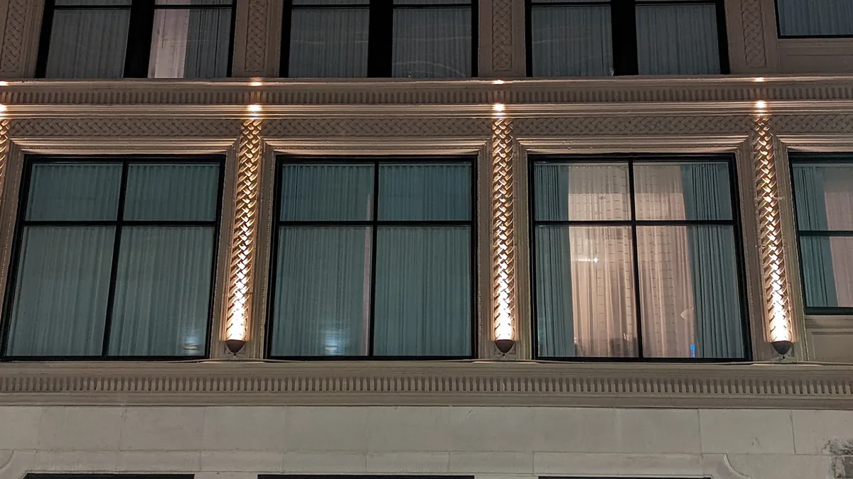 Historic hotel facade at night, ornamental stone pilasters lit from below by warm grazing uplights
